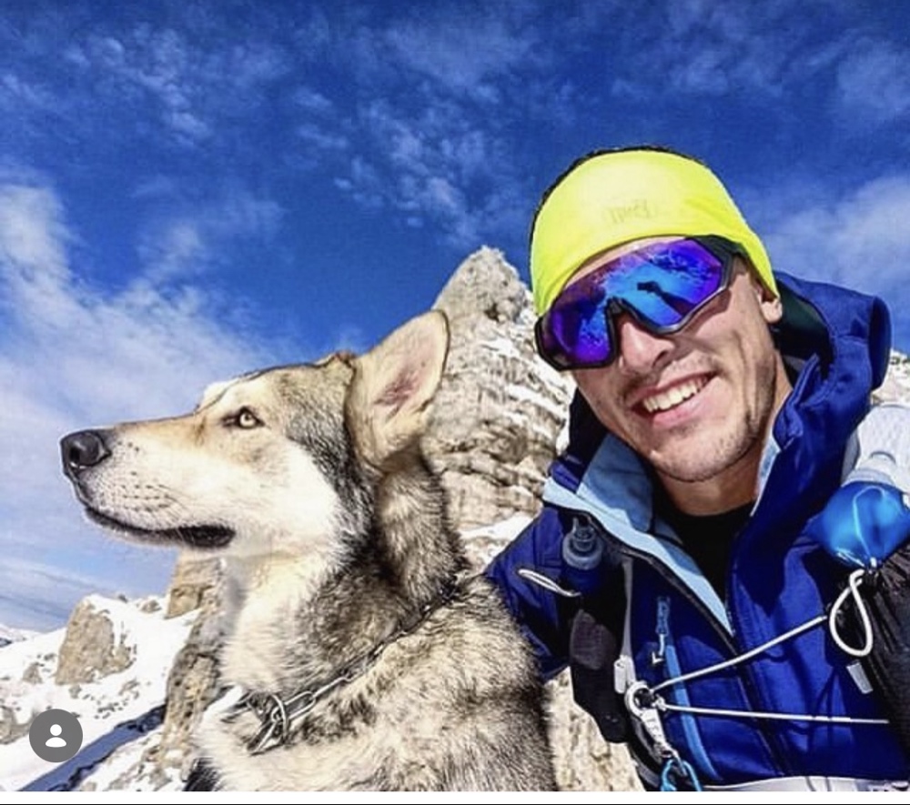 Deportista con gafas ISGLOW y su perro en la montaña